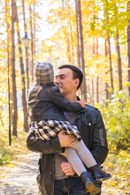 Vaderschap, kinderen en familieconcept - vader die zijn dochter in de herfstpark houdt