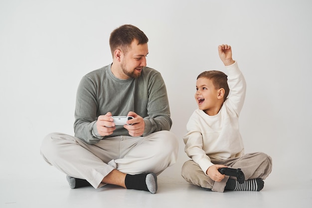 Vaderschap Vader en zoon spelen gamepad consolegame lachen en hebben samen plezier Gamers spelen computergames