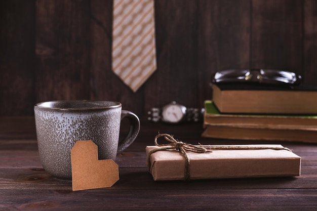 Vadersdag concept kartonnen hart bij een beker geschenk koppel boeken en glazen op de tafel