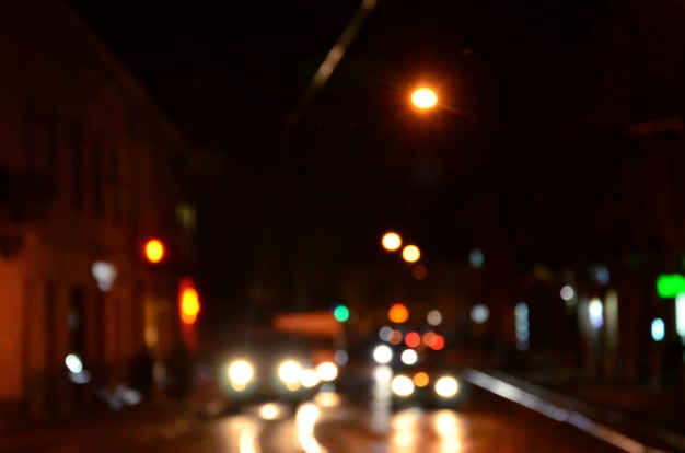 Vage nachtscène van verkeer op de rijweg. Defocused beeld van auto's die reizen met lichtgevende koplampen. Bokeh Art