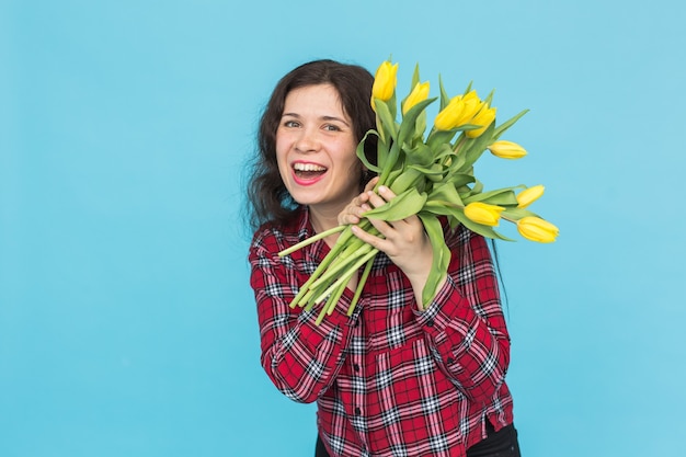 Vakantie, bloemen en mensen concept - grappig meisje in geruite overhemd met boeket tulpen in handen poseren