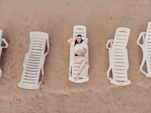 Vakantie en avontuur. Bovenaanzicht van drone op strand, strandstoel en relax meisje