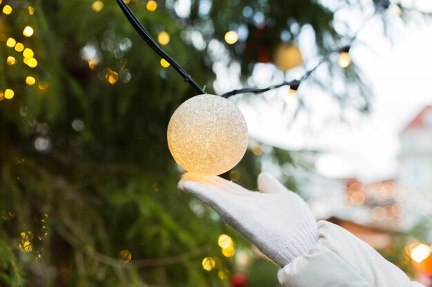 Foto vakantie- en decoratieconcept - close-up van de hand met kerstboomkransbollen buitenshuis