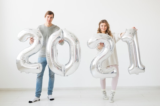 Vakantie-, feest- en feestconcept - Gelukkig liefdevol paar houdt zilveren 2021-ballonnen vast