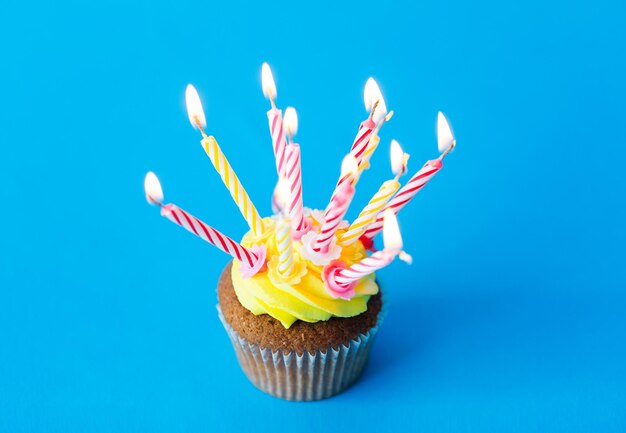 vakantie, feest, groet en feestconcept - verjaardag cupcake met veel brandende kaarsen op blauwe achtergrond