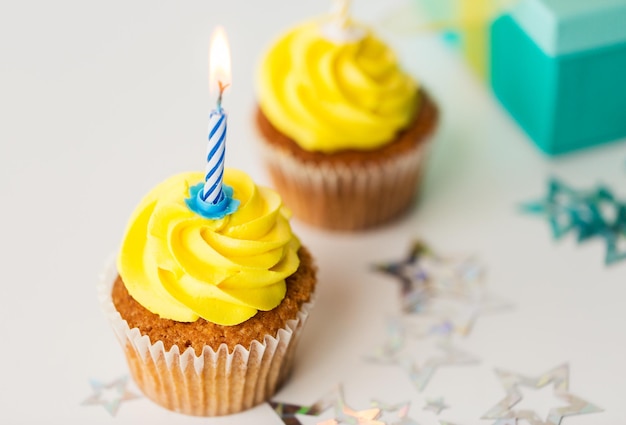 vakantie, feest, groet en feestconcept - verjaardag cupcakes met brandende kaarsen