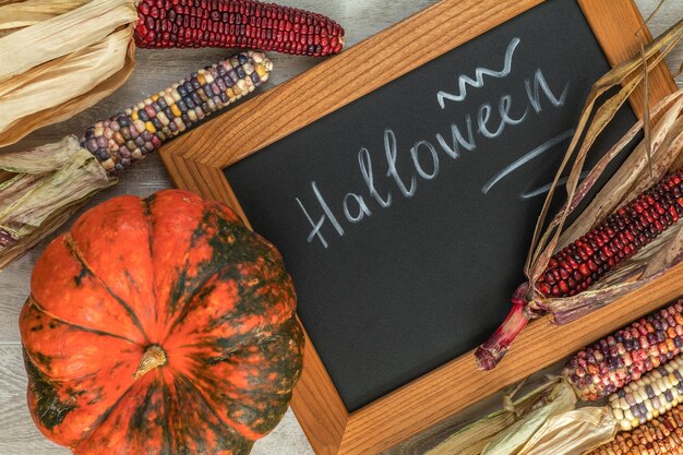 Vakantie Halloween-achtergrond met Indiase veelkleurige maïspompoen en leibord bovenaanzicht
