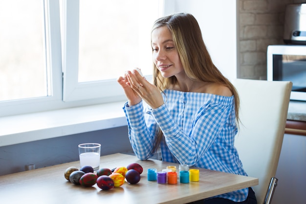 Vakantie, handgemaakt en creatie concept - Gelukkige jonge vrouw trekt op paasei.