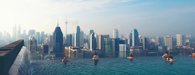 Vakantie in Kuala-Lumpur. De jonge vrouw geniet van zwemmend in dak hoogste pool met mooie stadsmening