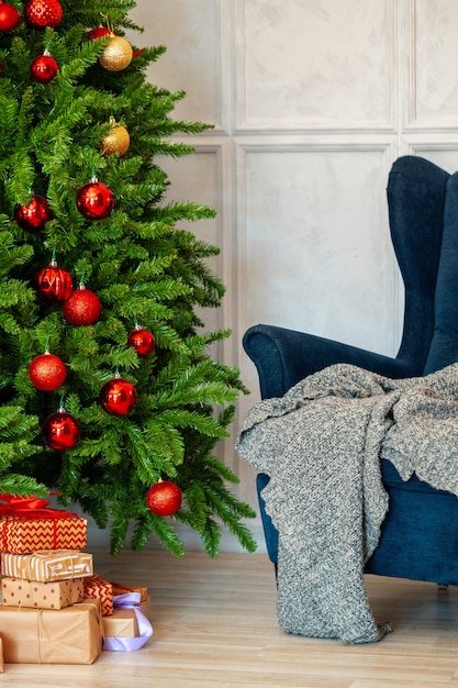 Vakantie interieur. Prachtig gedecoreerde kerstboom met blauwe fauteuil