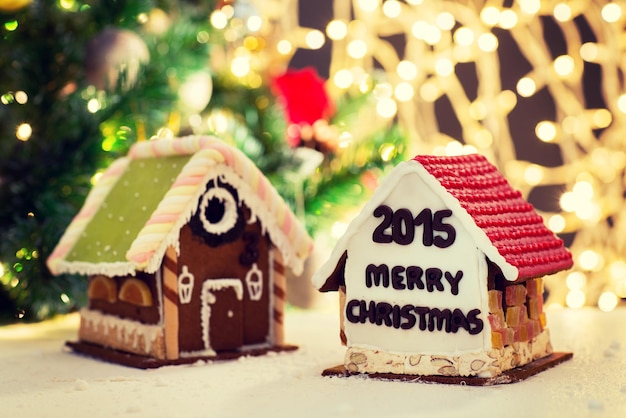 vakantie, kerst, bakken en snoep concept - close-up van mooie peperkoek huizen op tafel over lichten achtergrond