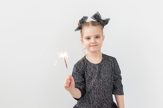 Vakantie, Kerstmis en Nieuwjaar concept - Gelukkig kind houdt een brandend sterretje in haar hand op een witte achtergrond met kopieerruimte.