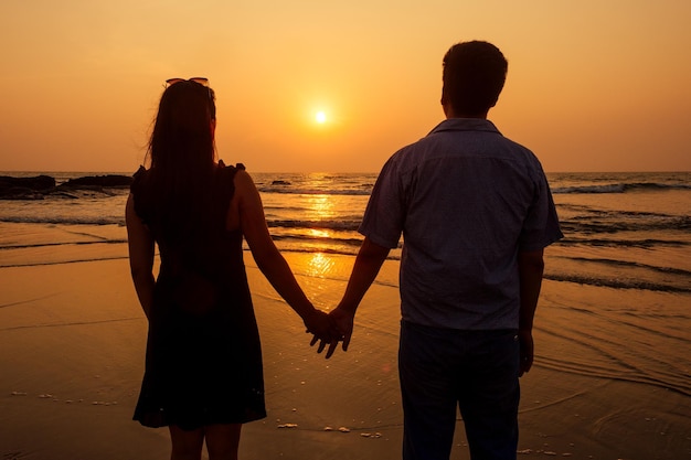 Vakantie paar wandelen op het strand samen verliefd bij zonsondergang goa