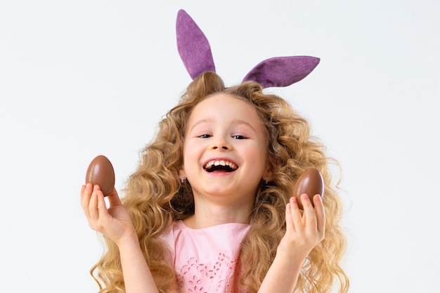 Vakantie pasen kinderen meisje met konijn haas konijnenoren spelen chocolade-eieren