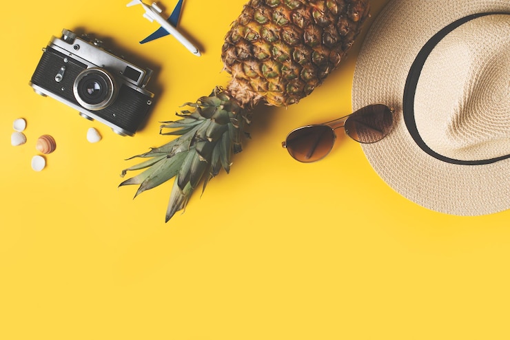 Foto vakantie plat zomervakantie en reizen met hoed zonnebril camera en ananas op gele achtergrond bovenaanzicht