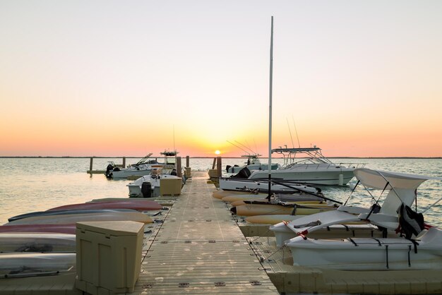 vakantie-, reis- en zeeconcept - boten afgemeerd aan de pier bij zonsondergang