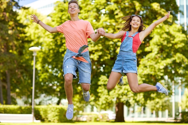 vakantie, vakantie, liefde en mensenconcept - gelukkig glimlachend tienerpaar die bij de zomerpark springen