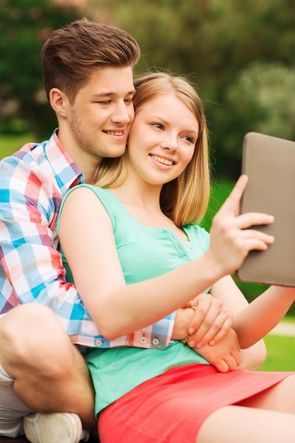 vakantie, vakantie, technologie en vriendschapsconcept - glimlachend paar die met de computer van tabletpc selfie in park maken