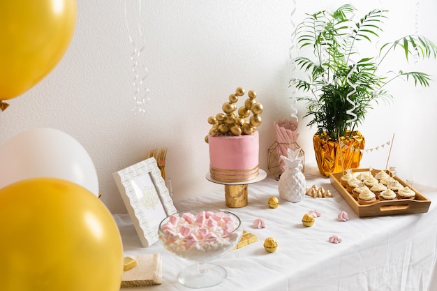 Vakantie verjaardagstafel met cake en ballons roze en gouden decoratie