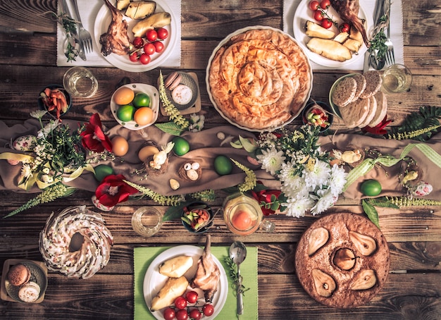 Vakantie vrienden of familie aan de tafel van de vakantie met konijnenvlees, groenten, taarten, eieren, bovenaanzicht.