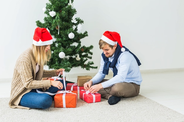 Vakantieconcept - Lief paar dat kerstcadeaus opent, zittend in de woonkamer.