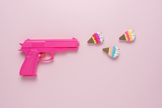 Vakantieconcept met roze pistool op roze pastelachtergrond met roomijsdecor