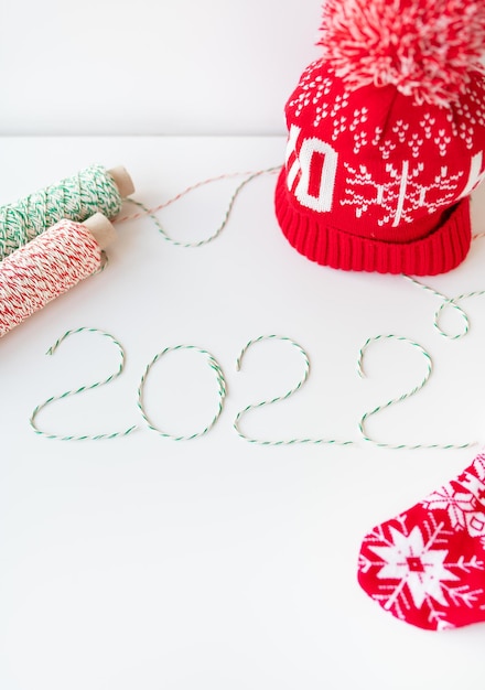 Vakantieconcept voor Kerstmis en Nieuwjaar 2022. Lay-out van verschillende kerstattributen - hoed, sok, gestreepte draden voor verpakking.