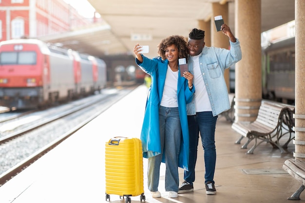 Foto vakantiereis vrolijke zwarte echtgenoten die selfie maken op het treinstation