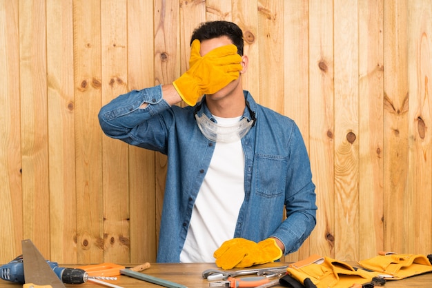 Vakliedenmens over houten muur die ogen behandelen door handen