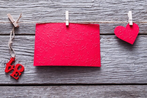 Valentijn met rood papier hart en lege wenskaart op wasknijpers op rustieke houten planken