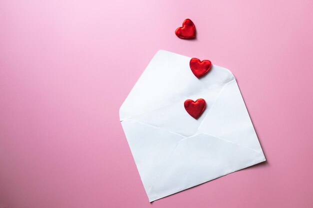 Foto valentijnsdag achtergrond blanke witte envelop met rode harten op roze achtergrond