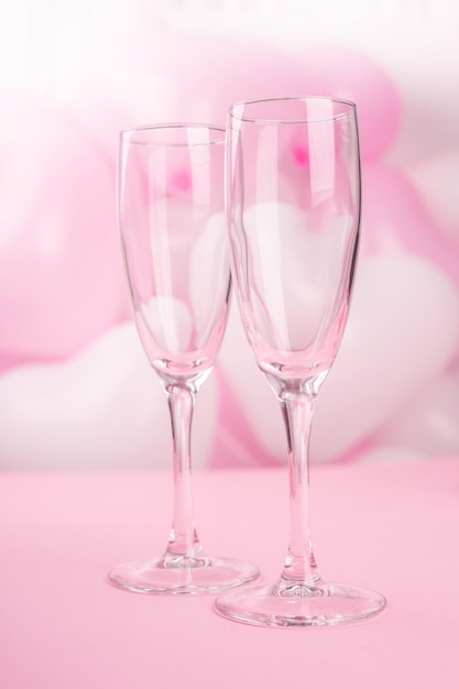 Foto valentijnsdag champagne fluiten glazen op roze ballonnen achtergrond met kopie ruimte voor tekst