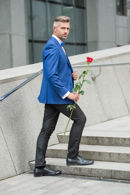 Valentijnsdag concept elegante smoking man met valentijnsroze bloem cadeau voor valentijnsdag