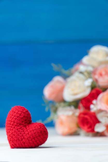 Valentijnsdag concept. hand maken garen rood hart voor roze bloemboeket op houten tafel