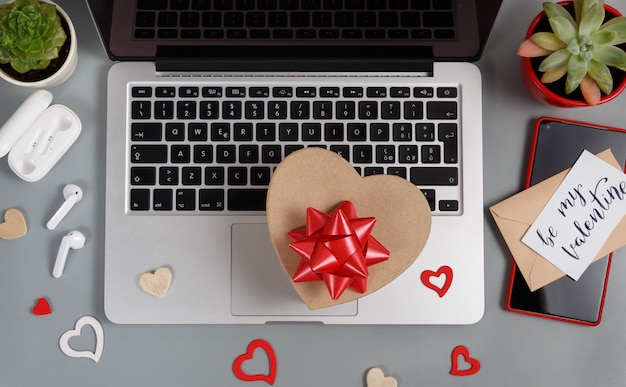 Valentijnsdag concept met moderne gadgets, geschenkdoos en BE MY VALENTINE kaart bovenaanzicht op grijze tafel