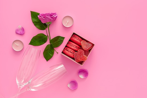 Valentijnsdag concept. Roze doos met marmelade en bitterkoekjes en een mooie roos op een roze tafel