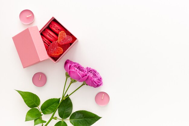 Valentijnsdag concept. Roze doos met marmelade en bitterkoekjes en een mooie roos op een roze tafel