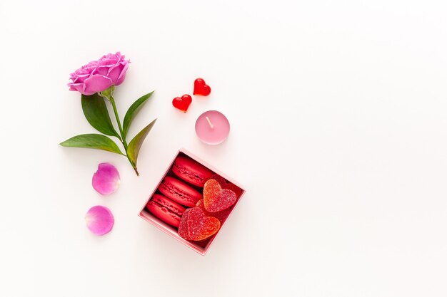 Valentijnsdag concept. Roze geschenkdoosje met marmelade en bitterkoekjes en een mooie roos