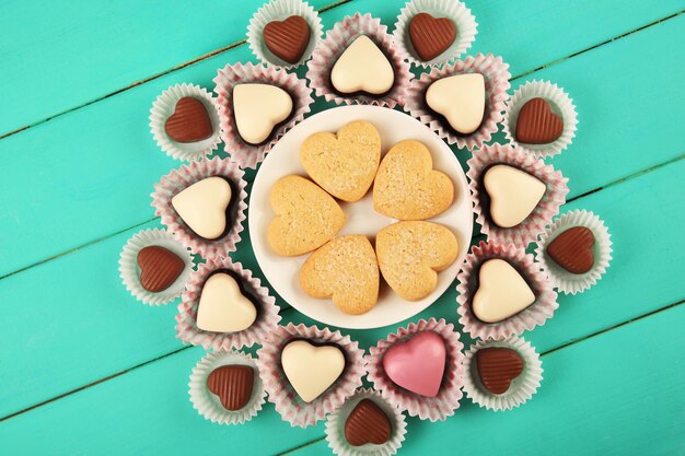 Valentijnsdag concept Samenstelling van heerlijke chocolade snoepjes en lekkere koekjes op turquoise houten achtergrond