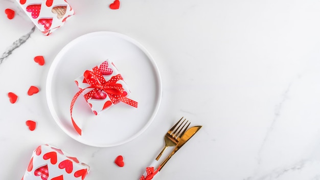 Valentijnsdag diner achtergrond met geschenken rode harten vork en mes op wit marmer romantisch