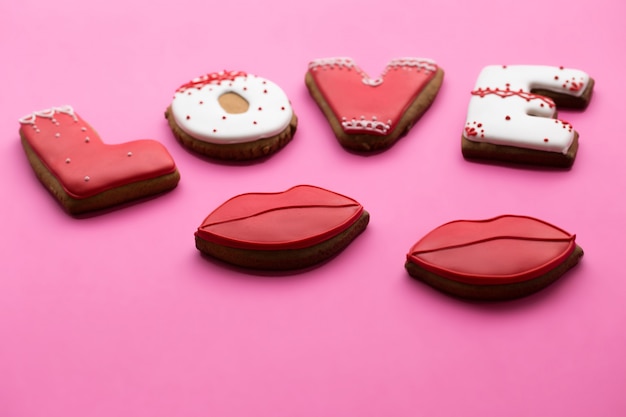 Valentijnsdag. Een koekje met liefdeharten, lippen op een roze achtergrond.