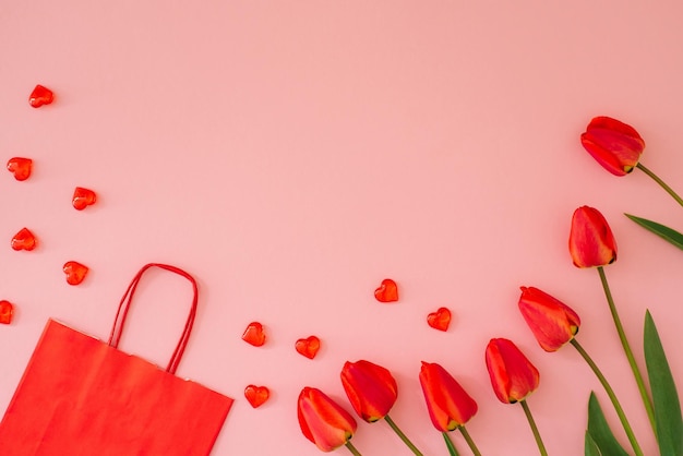 Valentijnsdag frame gemaakt van een boeket rode tulpenharten en een geschenk eco papieren zak