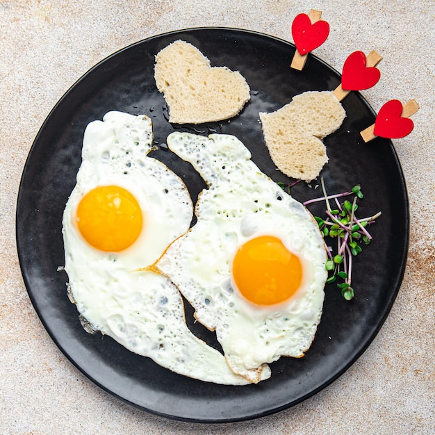 Valentijnsdag gebakken ei ontbijt op tafel roerei hartvorm vakantie