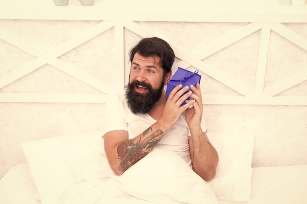 Foto valentijnsdag geschenk geluk verspreid liefde geschenk voor liefste gelukkige man ontspannen in bed maak een verrassingsconcept geschenk voor echtgenoot leuk en romantisch geschenk bearded hipster bereidt een prachtig geschenk voor