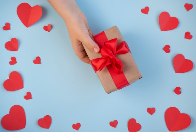 Valentijnsdag. Geschenk in de hand, een liefdesverklaring, een doos met een rood lint. Bovenaanzicht