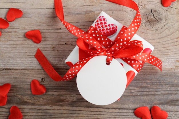 Valentijnsdag geschenk met ronde witte gift tag mockup op rustieke houten achtergrond met rood hart