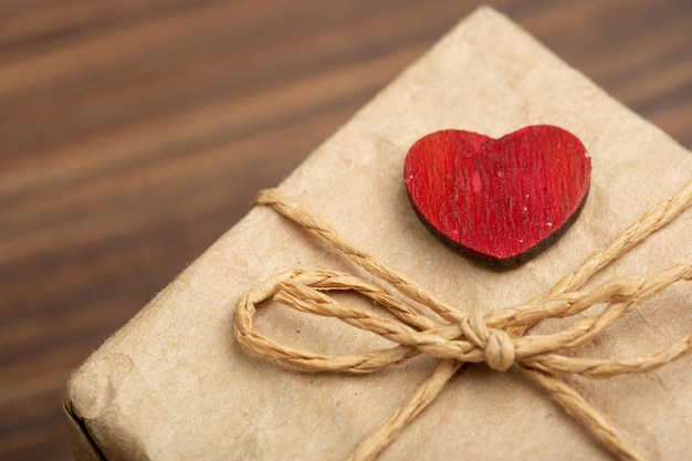 Valentijnsdag groeten concept Kleine rode houten bewerkte hart en geschenkdoos close-up op de houten achtergrond Valentines wenskaart