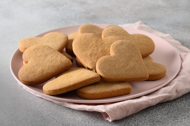 Valentijnsdag hartvormige koekjes op roze plaat op grijze achtergrond. Detailopname.