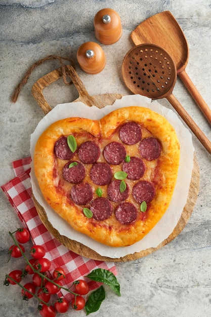 Valentijnsdag hartvormige pizza met mozzarella pepperoni en basilicum wijnfles twee wijnglas geschenkdoos op lichtgrijze achtergrond Idee voor romantisch diner Valentijnsdag Bovenaanzicht Mock up