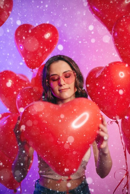 Valentijnsdag. Jonge aantrekkelijke vrouw met een hartvormige ballon in haar handen. Portret met gesloten ogen.